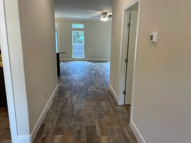 a view of a hallway with wooden floor and a bathroom