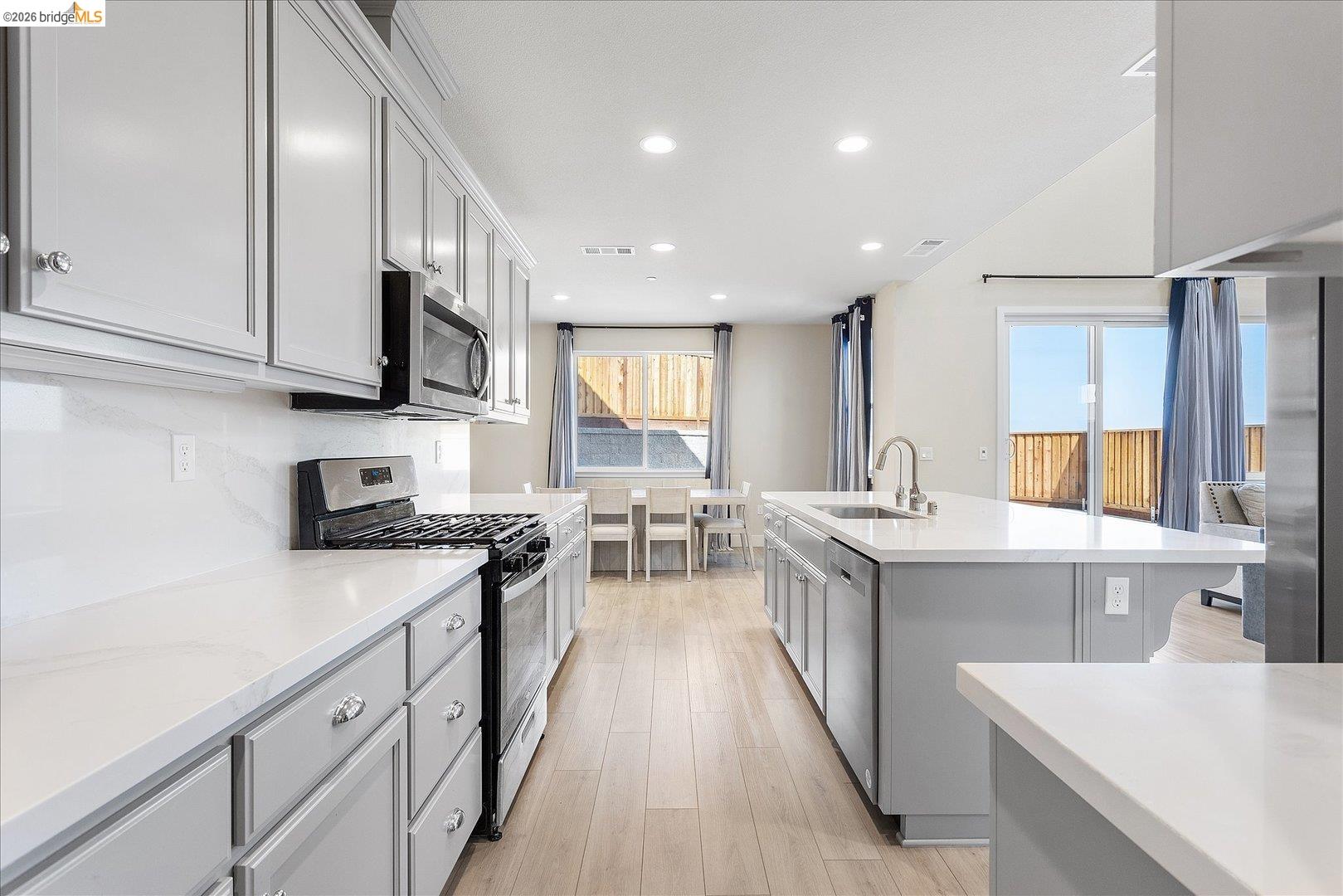 5601 Ridgepoint Way Antioch, CA 94531 - Photo 16 of 59 Contemporary kitchen featuring light wood-finish flooring, light grey cabinetry with polished hardware, white countertops, and stainless steel appliances