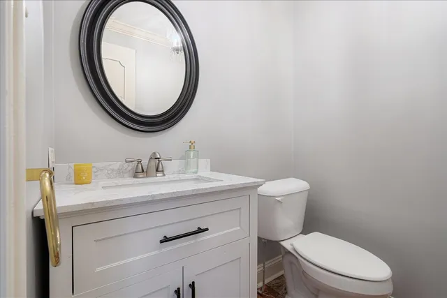 a bathroom with a granite countertop toilet a sink and a mirror