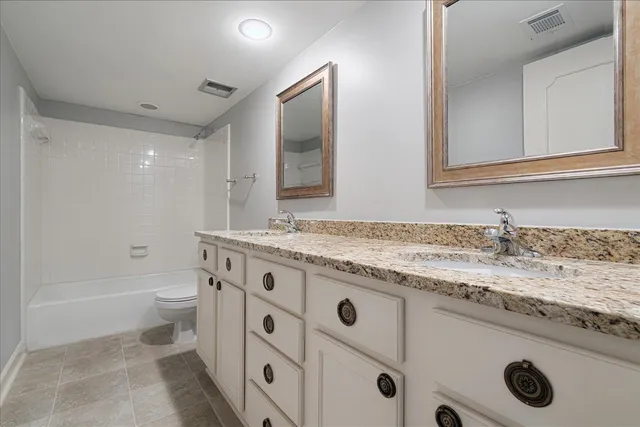 a bathroom with a granite countertop sink a toilet and a mirror
