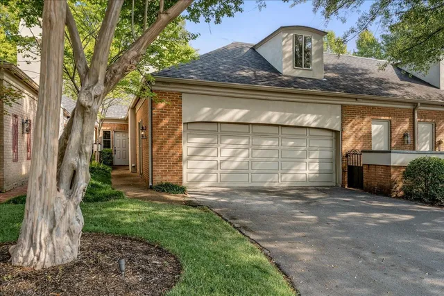 a view of a house with a small yard and large tree