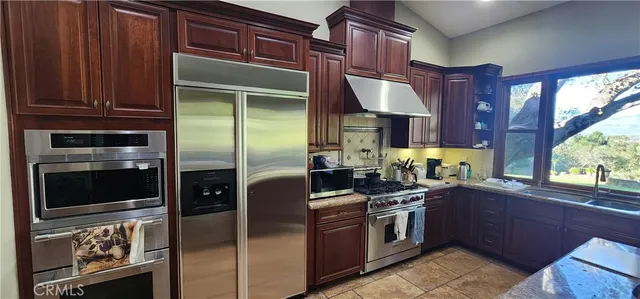 a kitchen with stainless steel appliances granite countertop a stove a refrigerator and a sink