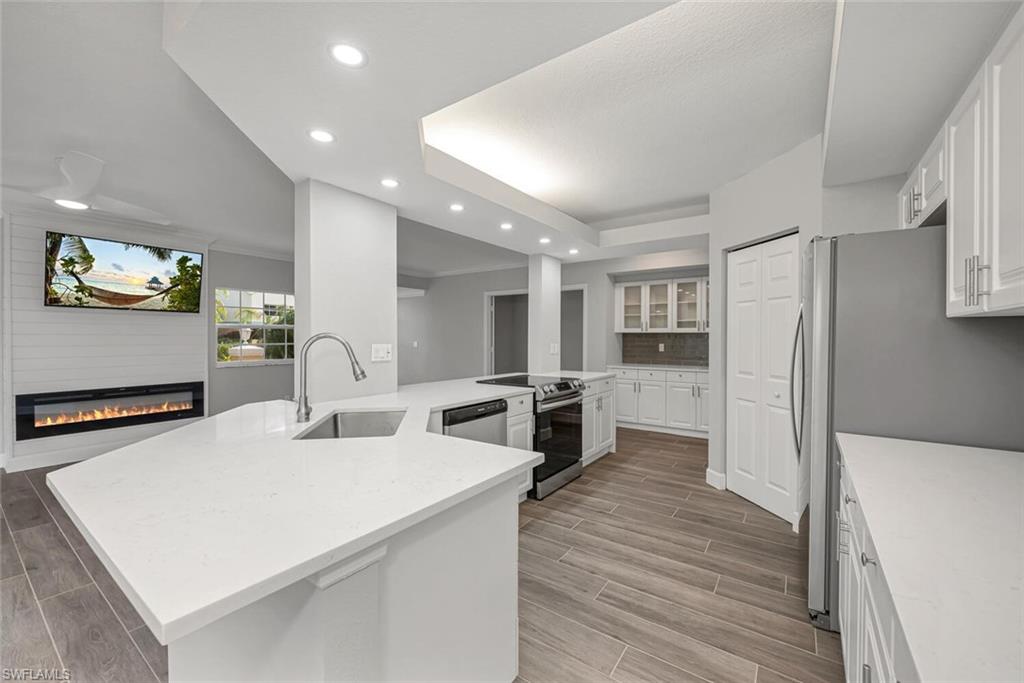 10771 Crooked River Road, Unit 103 Estero, FL 34135 - Photo 6 of 21 a kitchen with stainless steel appliances a refrigerator a sink dishwasher a oven with white cabinets and wooden floor