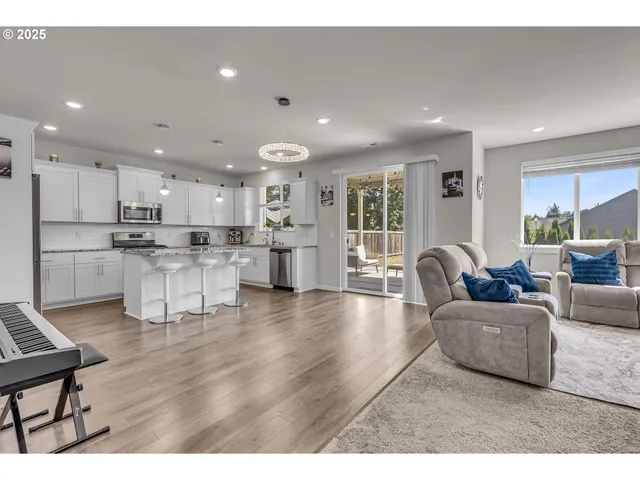 a living room with furniture and kitchen view with wooden floor
