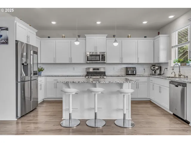 a kitchen with stainless steel appliances granite countertop a white cabinets and a refrigerator