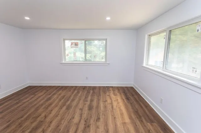 an empty room with wooden floor and windows