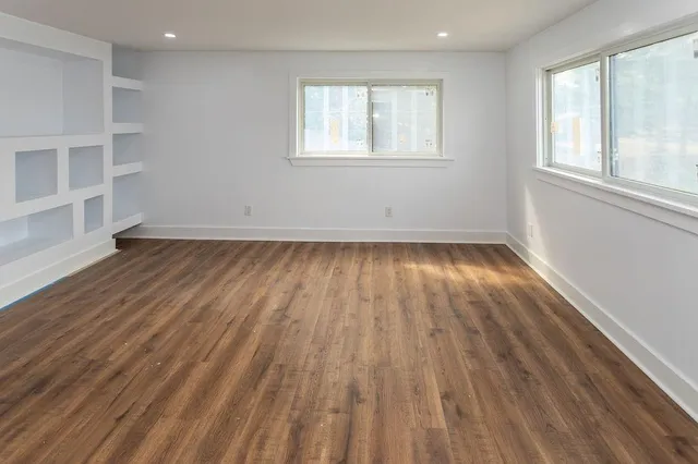 an empty room with wooden floor and windows
