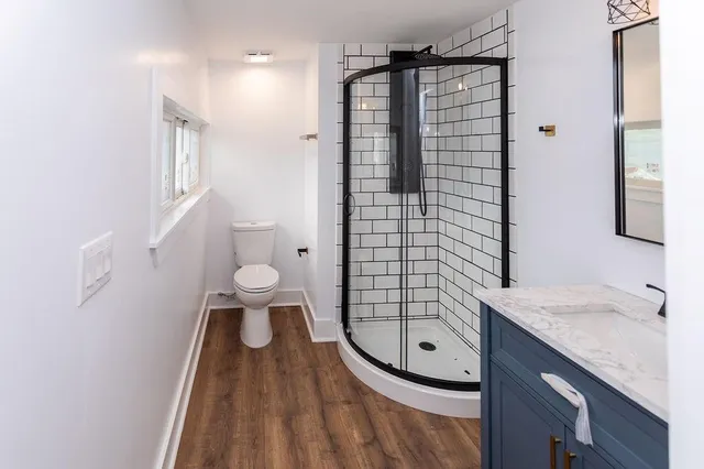 a bathroom with a granite countertop sink a toilet a mirror and shower