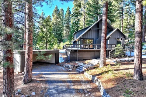 a view of house with yard outdoor seating and trees in the background