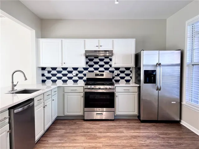 a kitchen with stainless steel appliances a stove a sink and a refrigerator