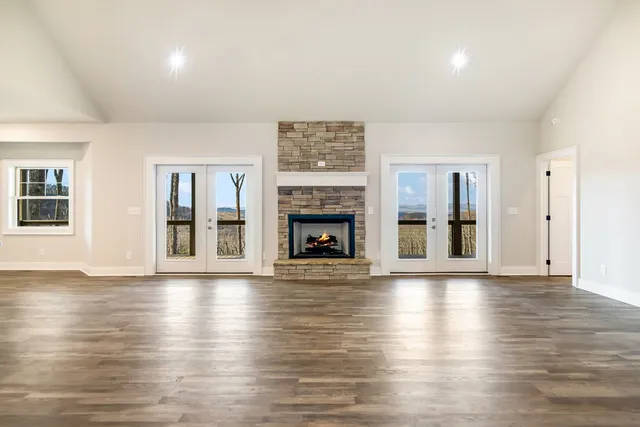 an empty room with wooden floor fireplace and windows