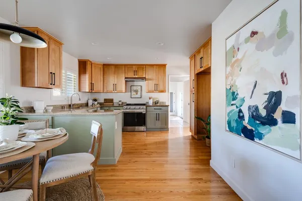 a kitchen with stainless steel appliances granite countertop a refrigerator a stove top oven a sink and dishwasher with wooden floor