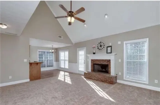 a view of a livingroom with a fireplace a ceiling fan and windows