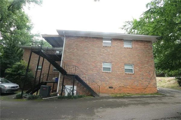 a view of a house with a yard plants and large tree