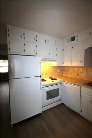 a kitchen with a refrigerator a sink and wooden floor