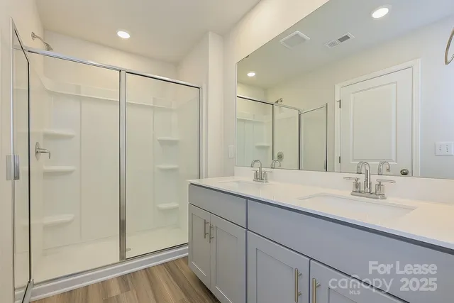 a bathroom with a double vanity sink mirror and shower