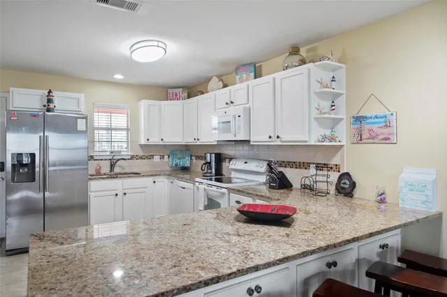 a kitchen with stainless steel appliances granite countertop a dining table chairs and view living room