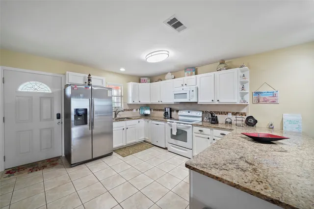 a kitchen with granite countertop a sink a stove and refrigerator