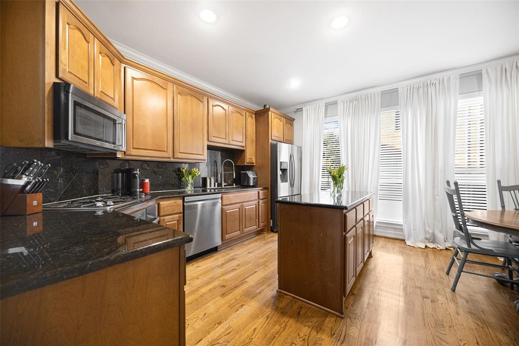 3610 Gillespie Street, Unit 6 Dallas, TX 75219 - Photo 13 of 27 a kitchen with stainless steel appliances granite countertop a refrigerator a stove top oven a sink dishwasher and wooden cabinets with wooden floor