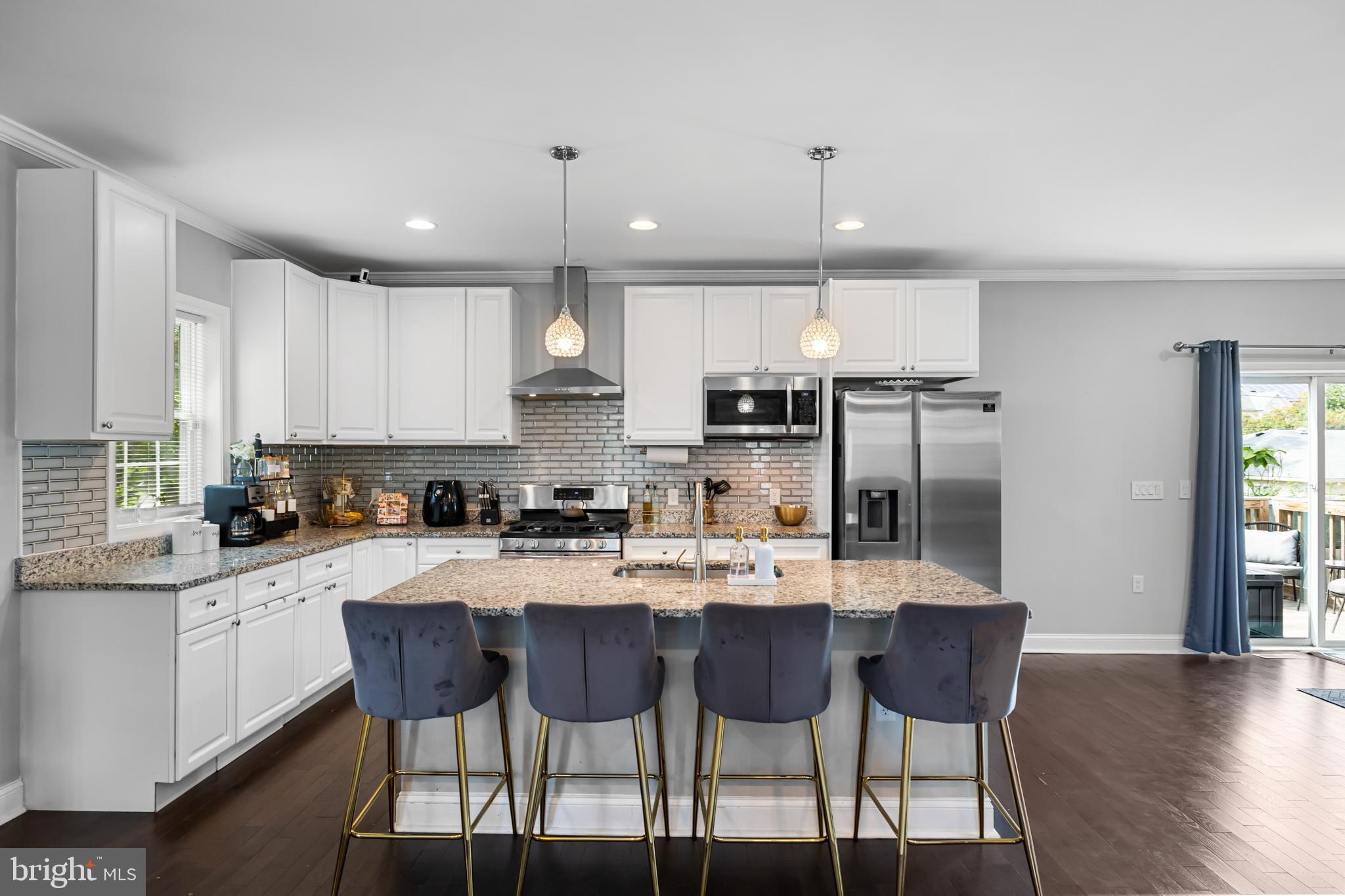 3327 5th Street Southeast Washington, DC 20032 - Photo 9 of 42 a kitchen with stainless steel appliances kitchen island granite countertop a dining table chairs and white cabinets