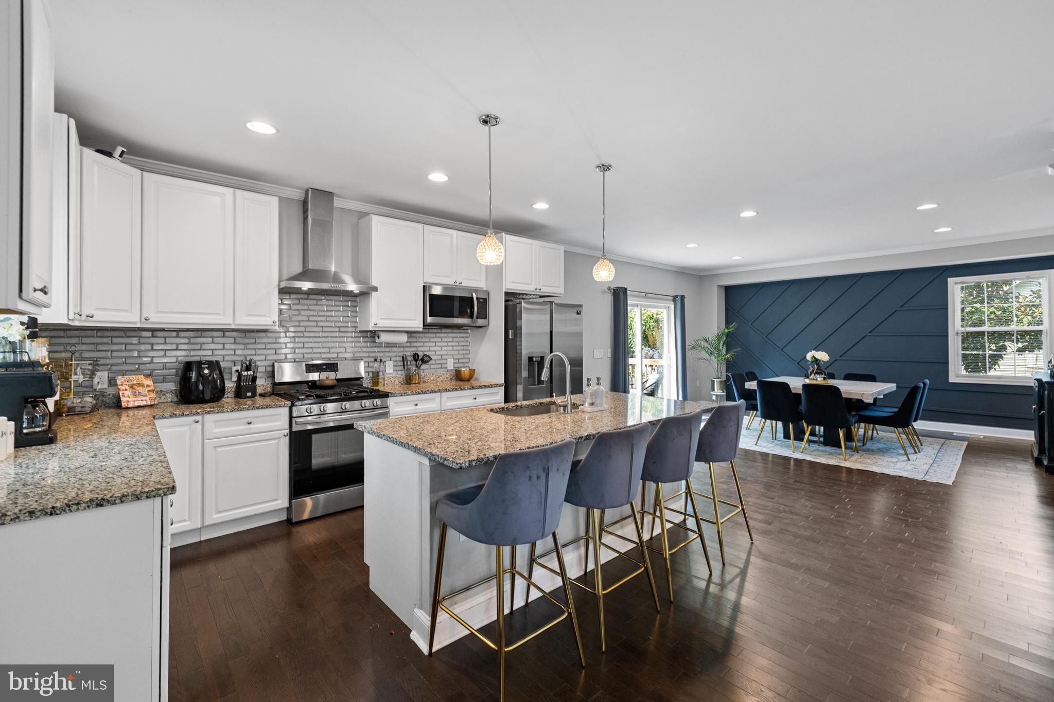 3327 5th Street Southeast Washington, DC 20032 - Photo 10 of 42 a kitchen with stainless steel appliances granite countertop a stove top oven a sink a dining table and chairs with wooden floor