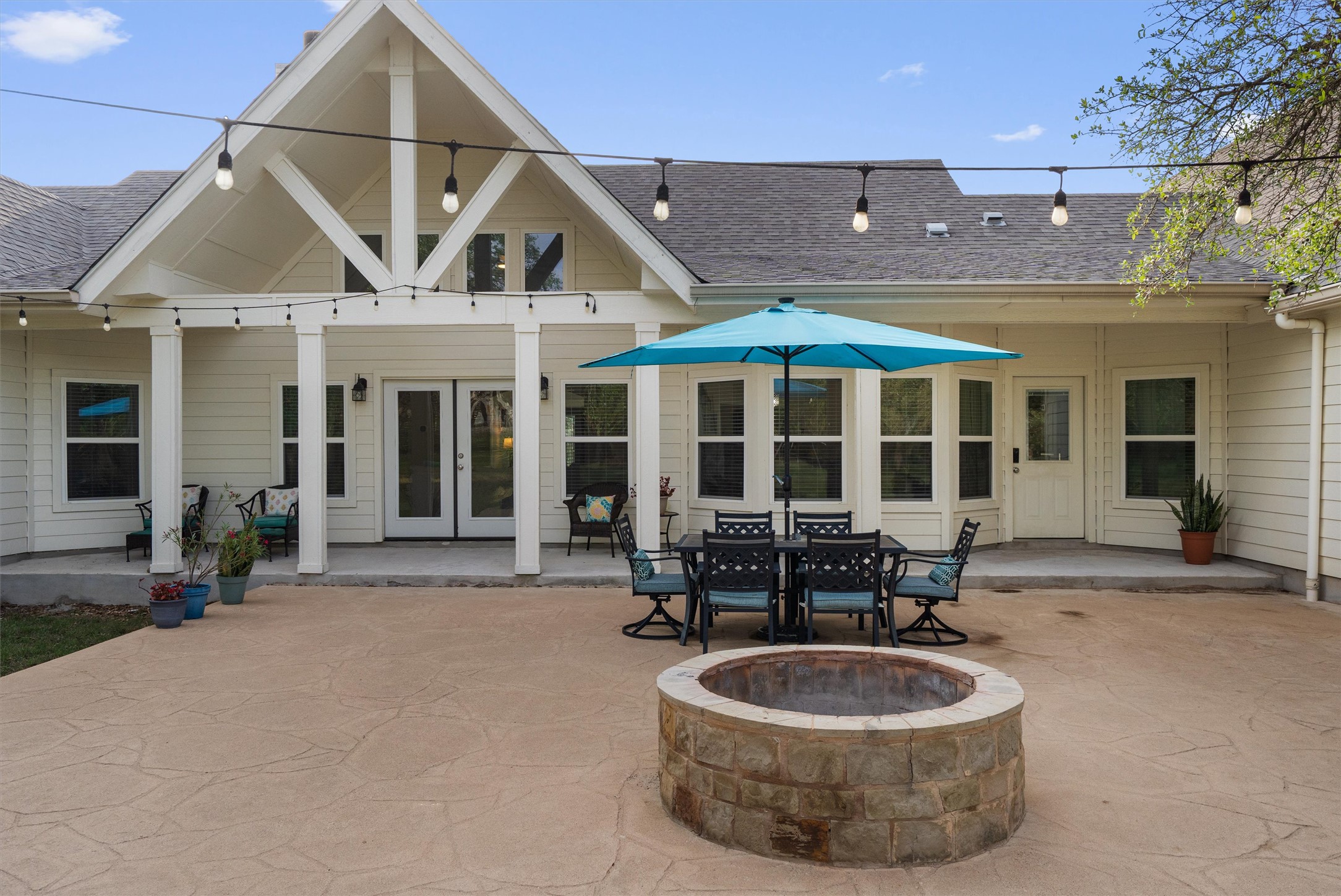 13105 Rooster Springs Road Austin, TX 78737 - Photo 23 of 38 The property features an extensive stamped concrete patio with a built-in fire pit and string lights