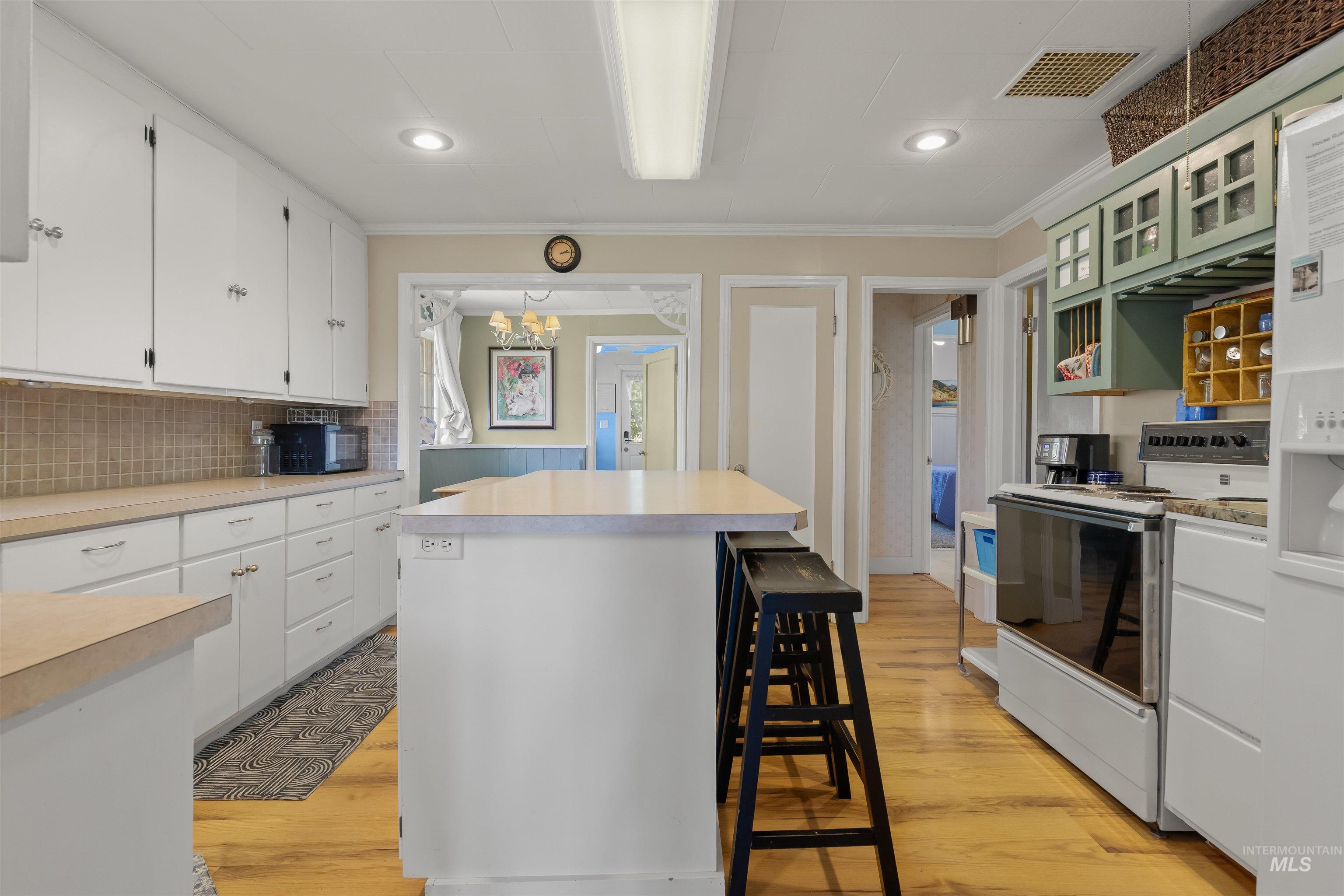 619 Prospect Avenue Lewiston, ID 83501 - Photo 14 of 37 Kitchen with wood-finish flooring, white cabinetry, integrated appliances, and a central island with breakfast bar seating