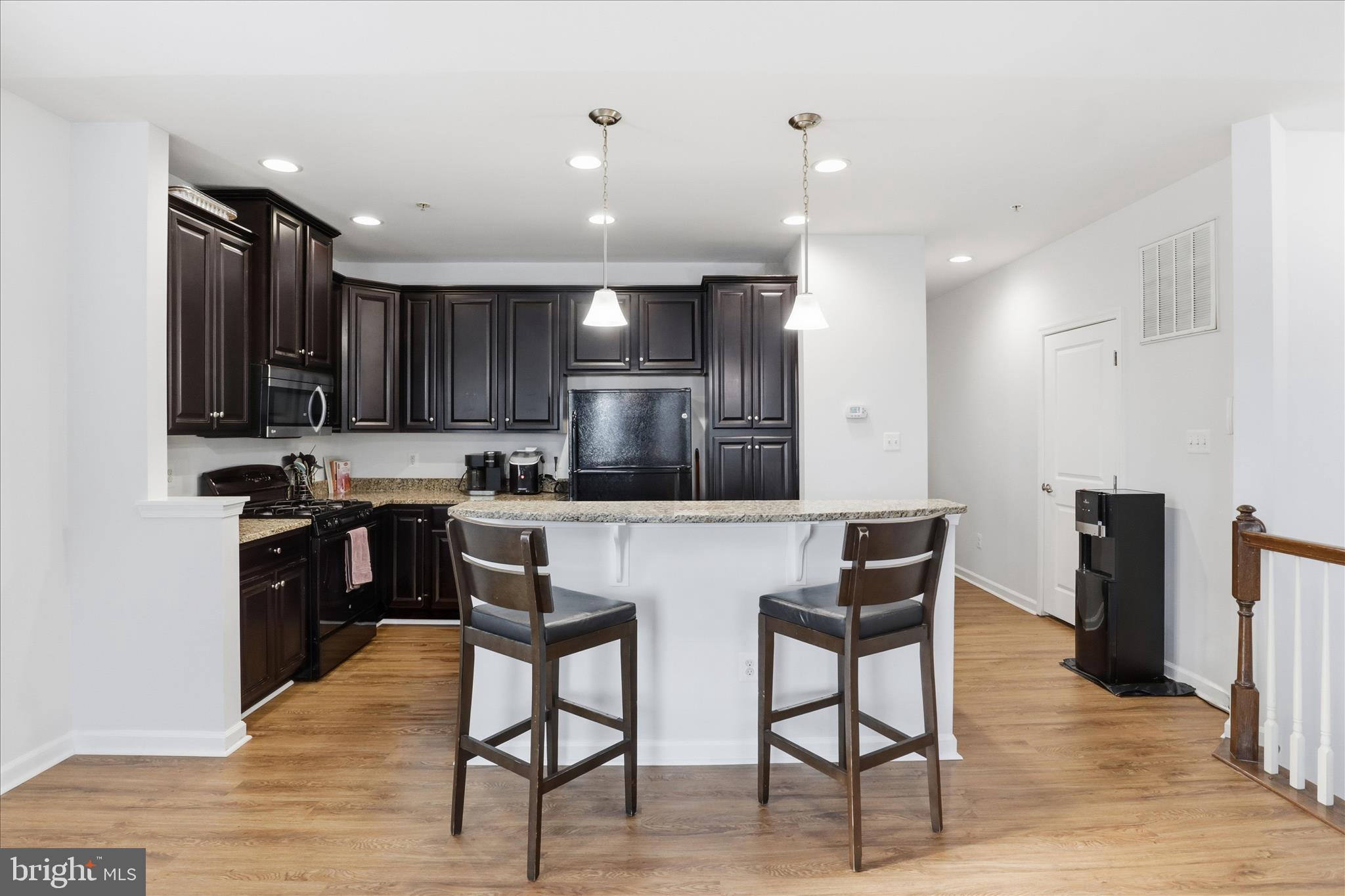 7455 Brunson Circle Gainesville, VA 20155 - Photo 13 of 41 a kitchen with stainless steel appliances granite countertop a refrigerator a stove top oven and a sink with wooden floor