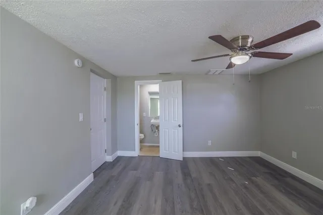 an empty room with wooden floor and a ceiling fan