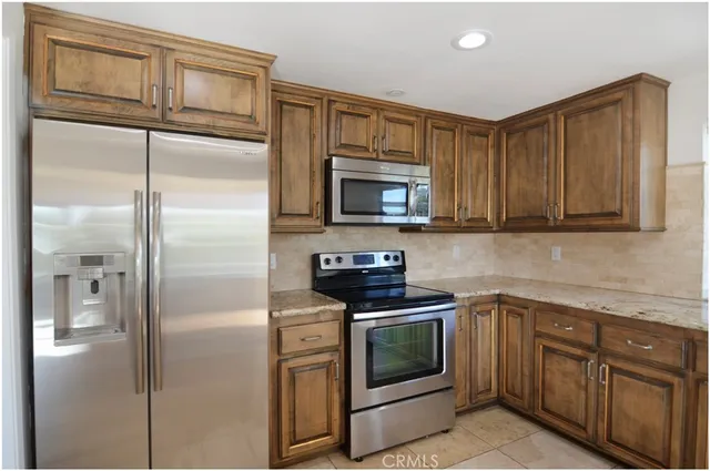 a kitchen with granite countertop a stove top oven cabinetry a sink and a microwave