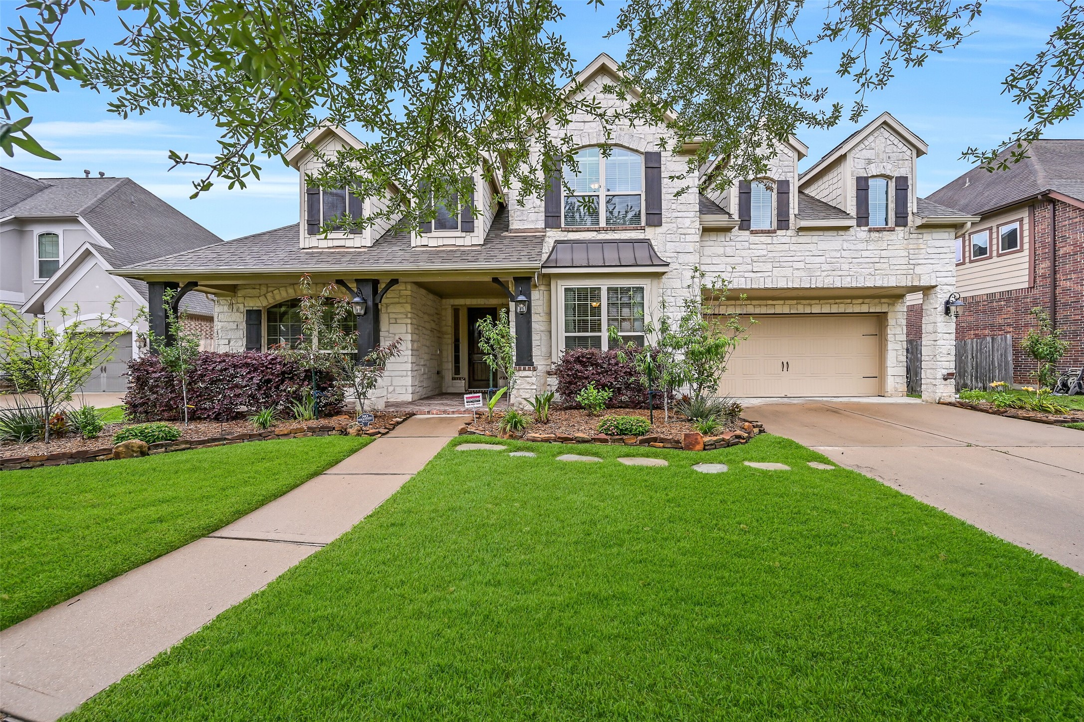 1008 Point Isabel Lane Friendswood, TX 77546 - Photo 2 of 50 A closer approach highlights the home’s crisp stone façade, charming shutters, and quaint covered porch, complemented by lush landscaping and a wide driveway leading to the attached 3-car tandem garage.