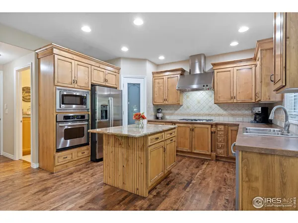 a kitchen with kitchen island granite countertop a sink cabinets and stainless steel appliances