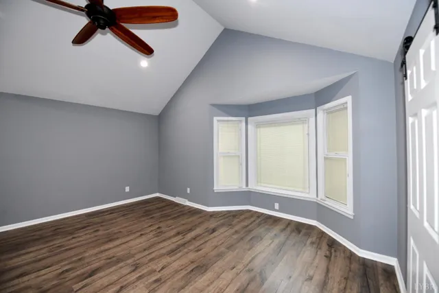 a view of an empty room with a window and wooden floor