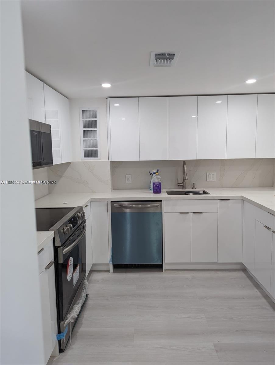 2801 Northeast 183rd Street, Unit 1709W Aventura, FL 33160 - Photo 3 of 6 a kitchen with granite countertop white cabinets and stainless steel appliances