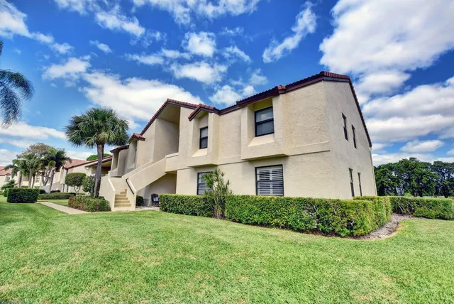 a view of a white house with a big yard plants and large trees