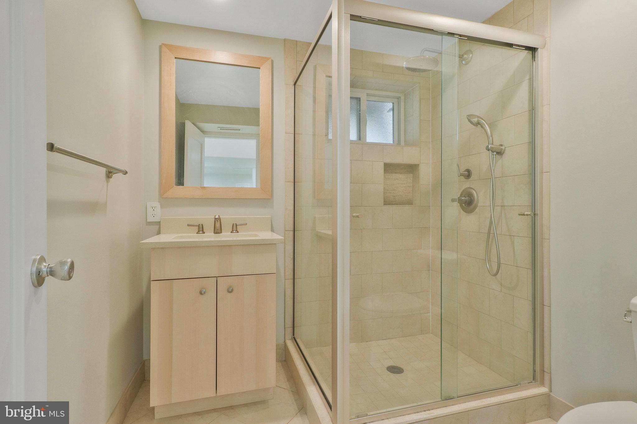 8543 Howell Road Bethesda, MD 20817 - Photo 20 of 24 a bathroom with a shower sink and mirror