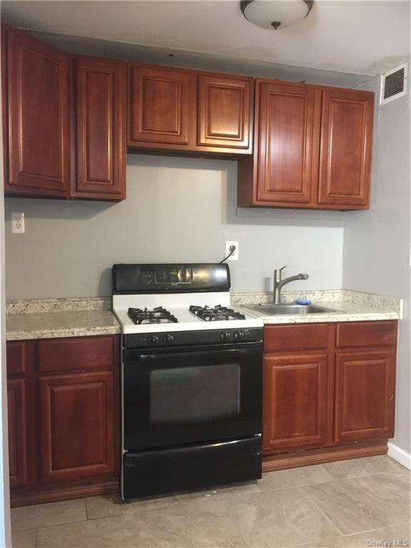a stove top oven sitting inside of a kitchen with granite countertop wooden cabinets