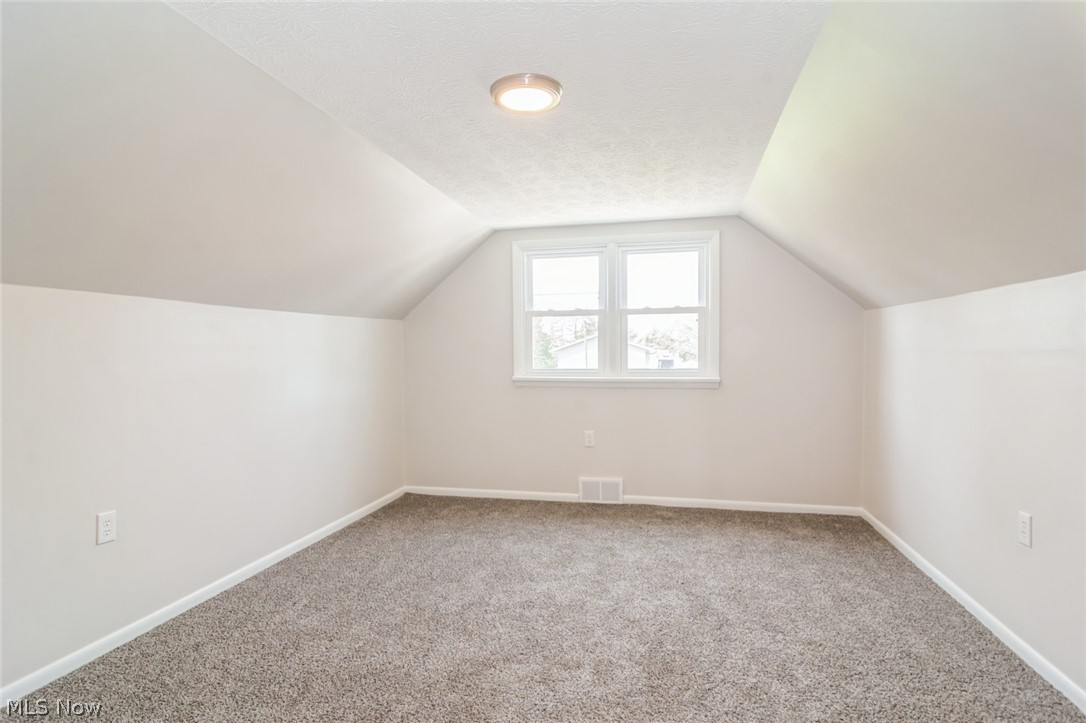 37012 Sugar Ridge Road North Ridgeville, OH 44039 - Photo 17 of 26 Additional living space featuring light colored carpet, a textured ceiling, and vaulted ceiling