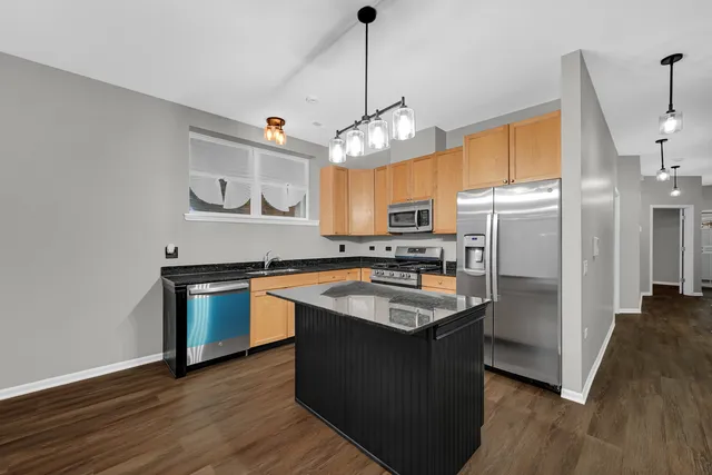 a kitchen with stainless steel appliances granite countertop a sink a counter space and wooden floor