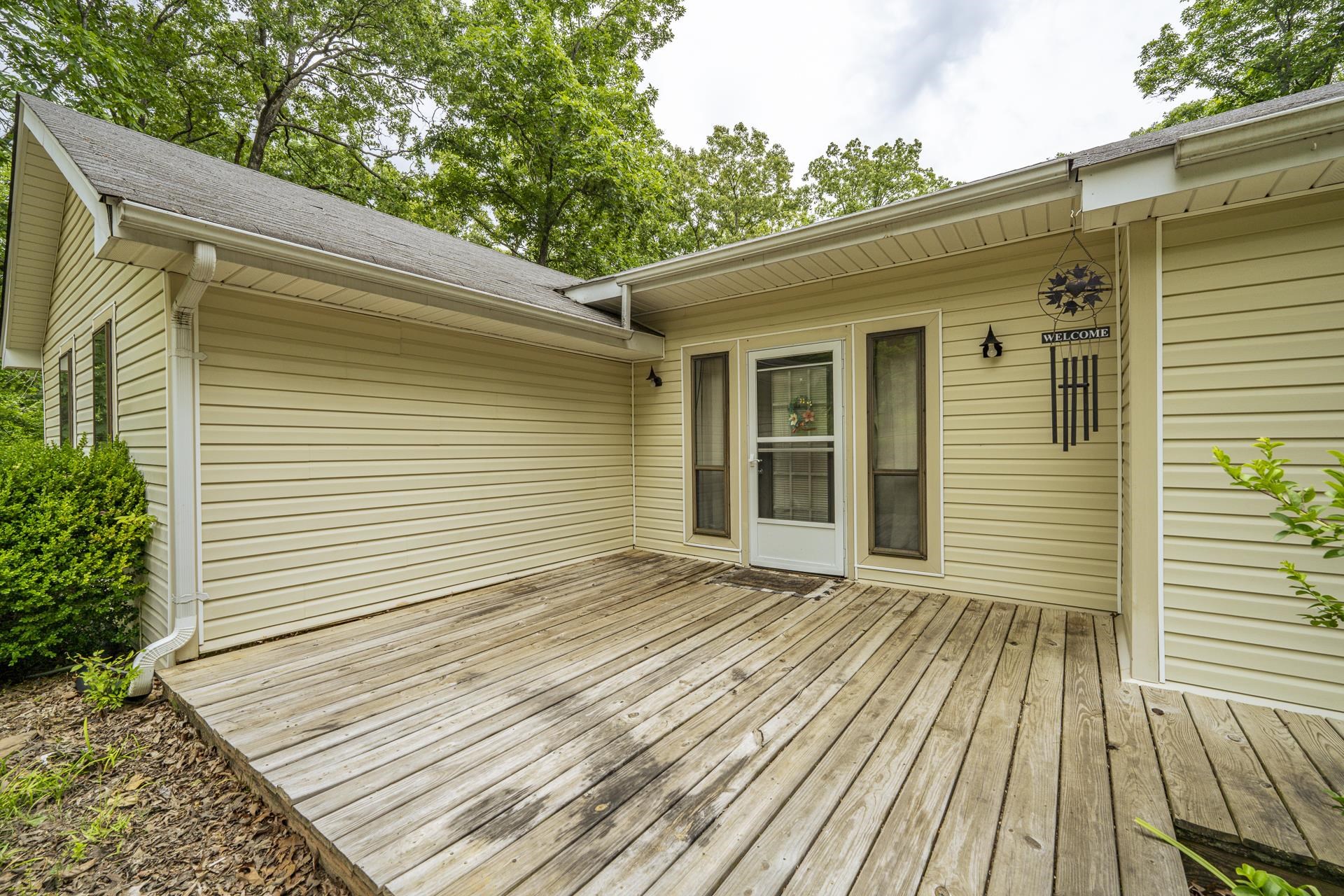 259 Oakview Drive Adamsville, TN 38310 - Photo 3 of 32 Expansive wood deck with direct entry, featuring durable vinyl siding, a gabled roofline, and integrated gutters