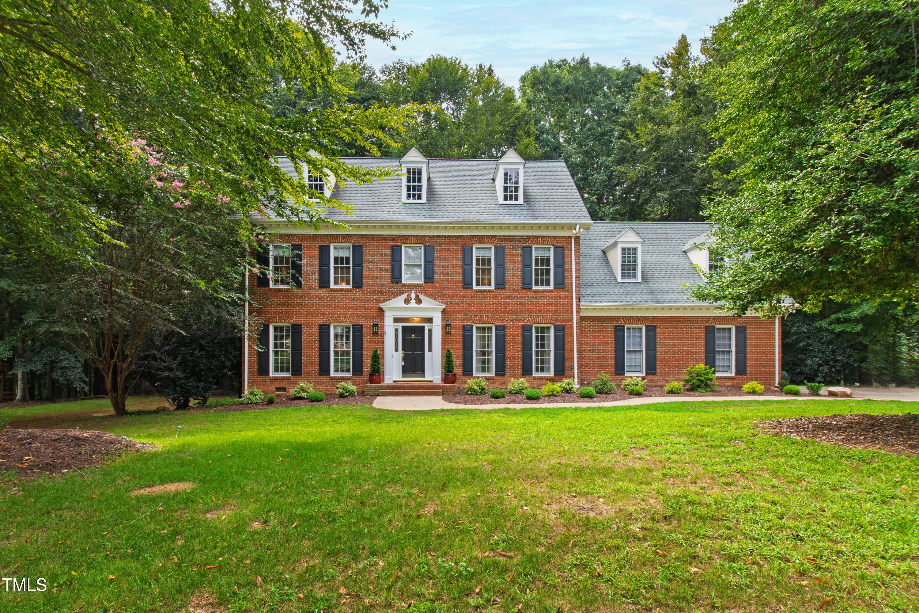 a front view of a house with a yard and trees