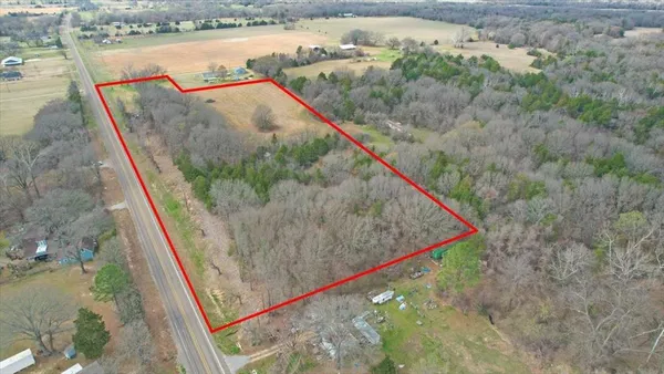 a view of a dry yard with trees in background