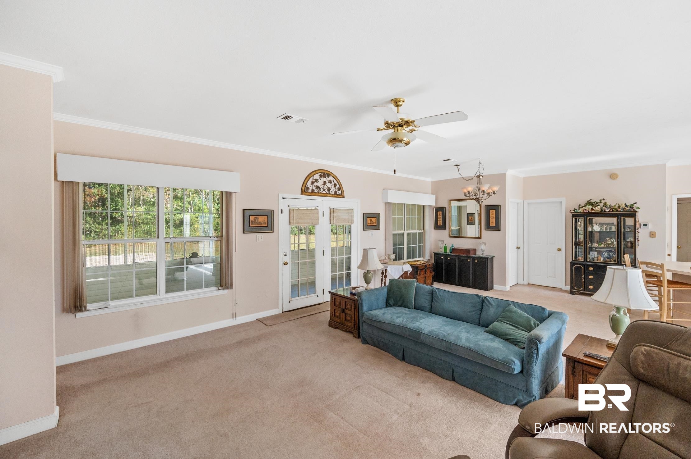 9260 Bay Point Drive Elberta, AL 36530 - Photo 22 of 34 Carpeted living room featuring ornamental molding and ceiling fan with notable chandelier