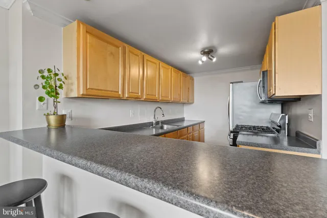 a kitchen with stainless steel appliances granite countertop a sink a stove and a granite counter tops with wooden floors