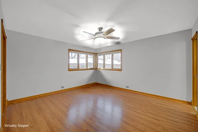 a view of empty room with wooden floor and fan