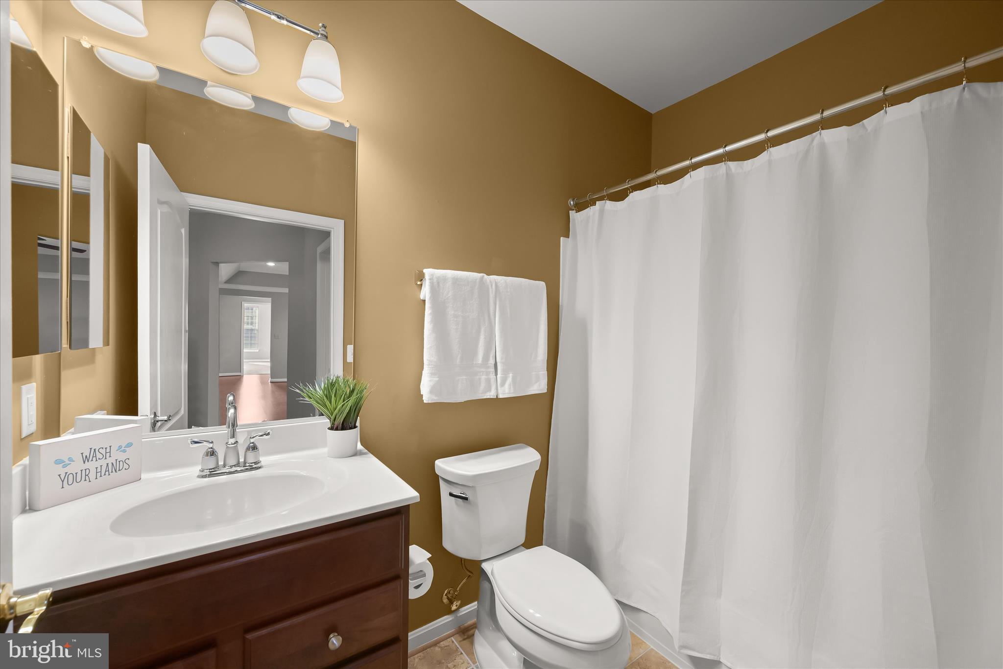 7305 Maplecrest Road, Unit 207 Elkridge, MD 21075 - Photo 36 of 50 a bathroom with a sink a toilet a mirror and shower curtain