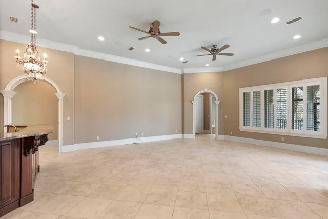 a view of an empty room with glass door and chandelier fan