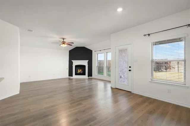 an empty room with wooden floor fireplace and windows