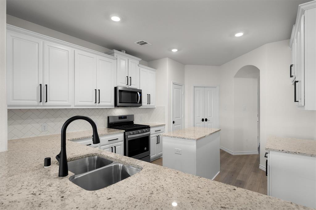 505 Maverick Street Anna, TX 75409 - Photo 20 of 39 a kitchen with stainless steel appliances granite countertop a white stove top oven and sink