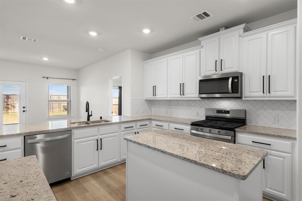 505 Maverick Street Anna, TX 75409 - Photo 21 of 39 a kitchen with a sink a stove and cabinets